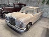 two old cars that are parked in a garage