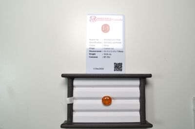 une pierre orange posée sur une étagère, à côté d'un porte-cartes de visite