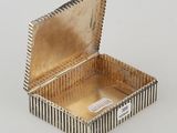 an open silver box sitting on top of a white surface