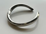 silver plated cuff bracelet with curved design on a white surface