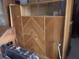 a wooden cabinet with a glass door and a suitcase in front of it