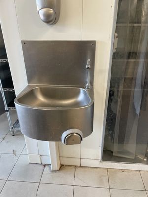 un évier en acier inoxydable dans le coin d'une salle de bains