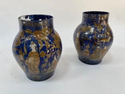 une paire de vases bleus et dorés posés sur une surface blanche