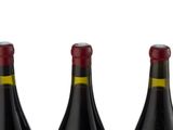 three bottles of wine are lined up in a row on a white surface