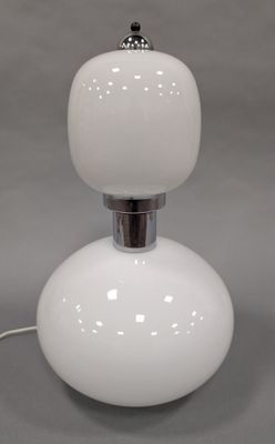 un gros plan d'une lampe de table blanche posée sur une surface grise