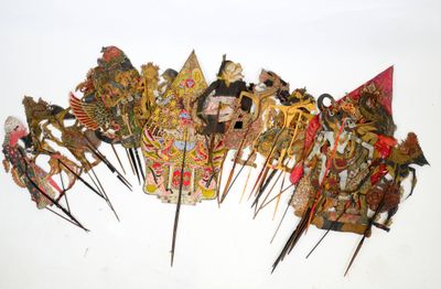 de nombreux types de masques fixés sur des tiges, disposés sur une surface blanche
