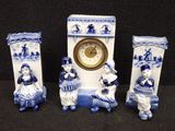 three blue and white figurines are sitting next to a clock