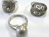 three silver rings and a silver ball on a white surface