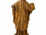 une vieille statue représentant un homme tenant un livre et portant un chapeau