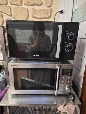 someone is taking a picture of a microwave on a small table