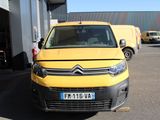 une camionnette Citroën jaune garée devant un immeuble, sur un parking