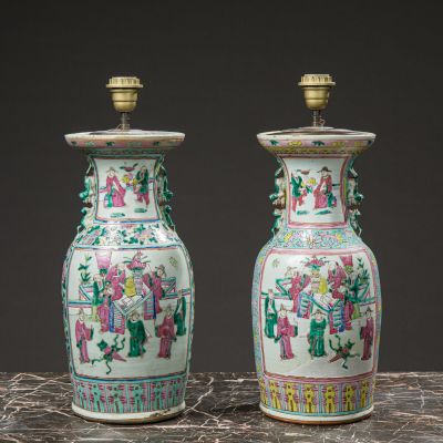 pair of chinese vases with figures on them sitting on a table