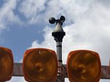 several orange lights on a metal pole with trees in the background
