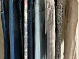 several pairs of jeans hanging on a rack in front of a mirror