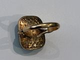 a gold ring with a coin in it on a white surface
