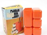 a box of orange plastic blocks sitting next to a box of pencils