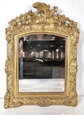 un miroir doré surmonté d'un oiseau