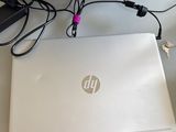 une personne debout à côté d'un ordinateur portable posé sur un bureau