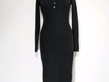 La robe est noire et comporte des boutons au niveau du cou.