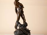 bronze statue of a naked man on a rock with a dog