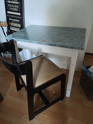 a small table with a chair and a chalk board on the wall
