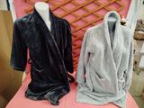 two robes on a mannequin on a pink table