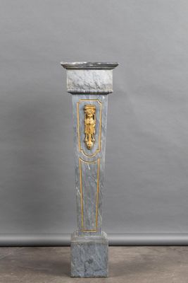 a marble pedestal with a gold lion head on it