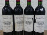 quatre bouteilles de vin sont alignées sur une table en bois