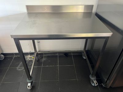 une table en acier inoxydable équipée de roulettes, dans une cuisine