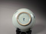 a blue and white bowl on a stand with a clock on it