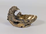 une image représentant une figurine en bronze d'un aigle posé sur un coquillage
