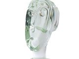 une sculpture en verre représentant la tête d'un homme, posée sur un socle transparent