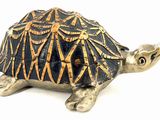 une petite figurine de tortue posée sur une surface blanche