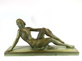 bronze statue of a woman laying on a marble base