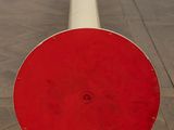 a red and white object on the floor next to a white pole