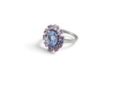 a close up of a ring with a blue stone surrounded by purple stones