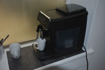 a black coffee machine sitting on top of a counter next to a cup