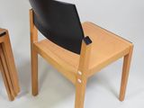two wooden chairs with a black leather seat on them