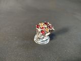 a silver ring with red stones on it on a black surface
