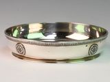 a silver bowl with a design on it on a white surface
