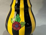 vase rayé de jaune et de noir, orné de fleurs sur un fond gris