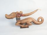 a wooden sculpture of a dog with a bone in it ' s mouth