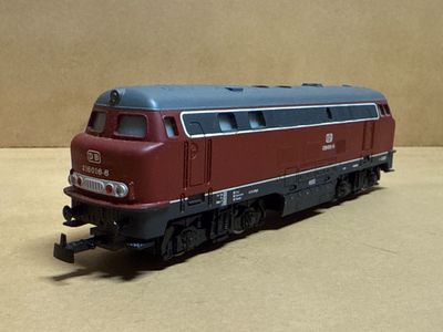 a red and blue train on the tracks on a tan surface