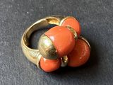 an image of a gold and coral colored ring on a black surface