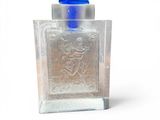 a small glass bottle with a blue lid on a white surface