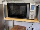 a microwave and a cutting board on a shelf in a kitchen
