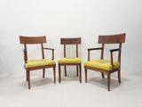 two wooden chairs with yellow upholstered cushions in a white room