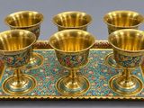 four gold cups on a tray with a tray underneath them