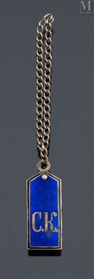 silver and blue enamel charm with a chain on a gray background