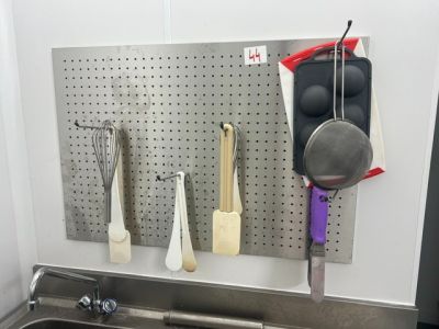 a kitchen sink with a bunch of utensils hanging on the wall